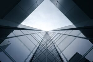 A dramatic upward view of a sleek glass skyscraper reflecting the sky, symbolizing modern finance and innovation. The image echoes the high-rise momentum surrounding Chime Financial’s electrifying debut on the Nasdaq in New York.